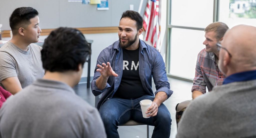Man talking to a group of people sitting in a circle
